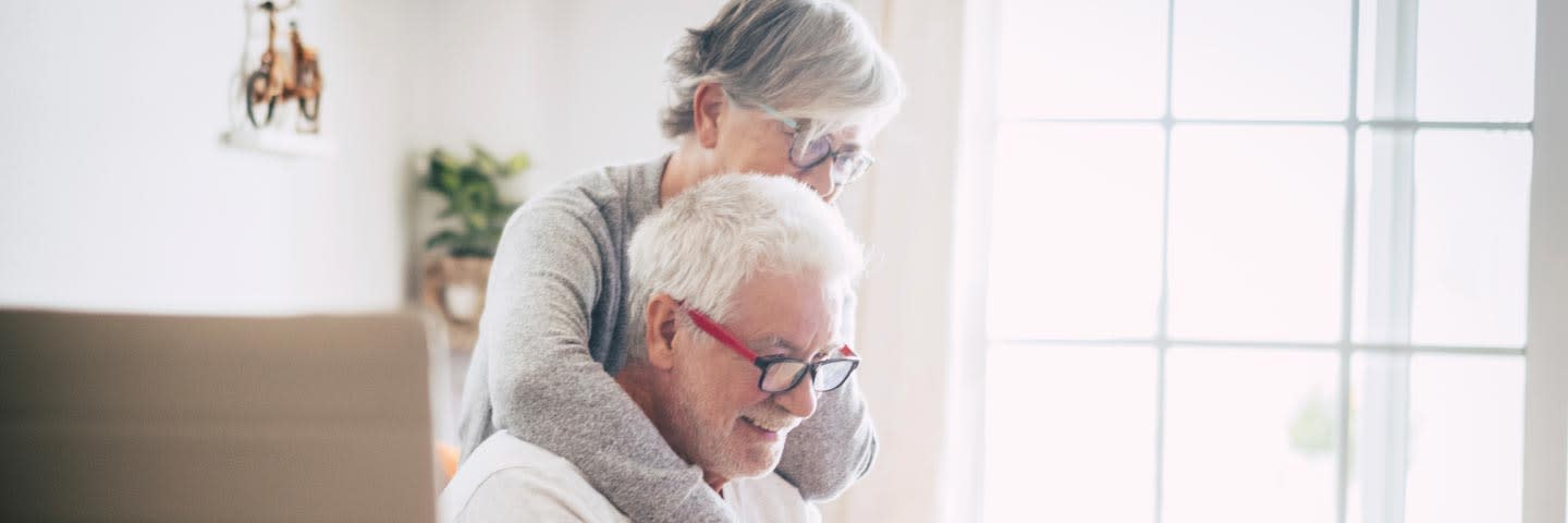 Elderly couple in kitchen looking at computer together