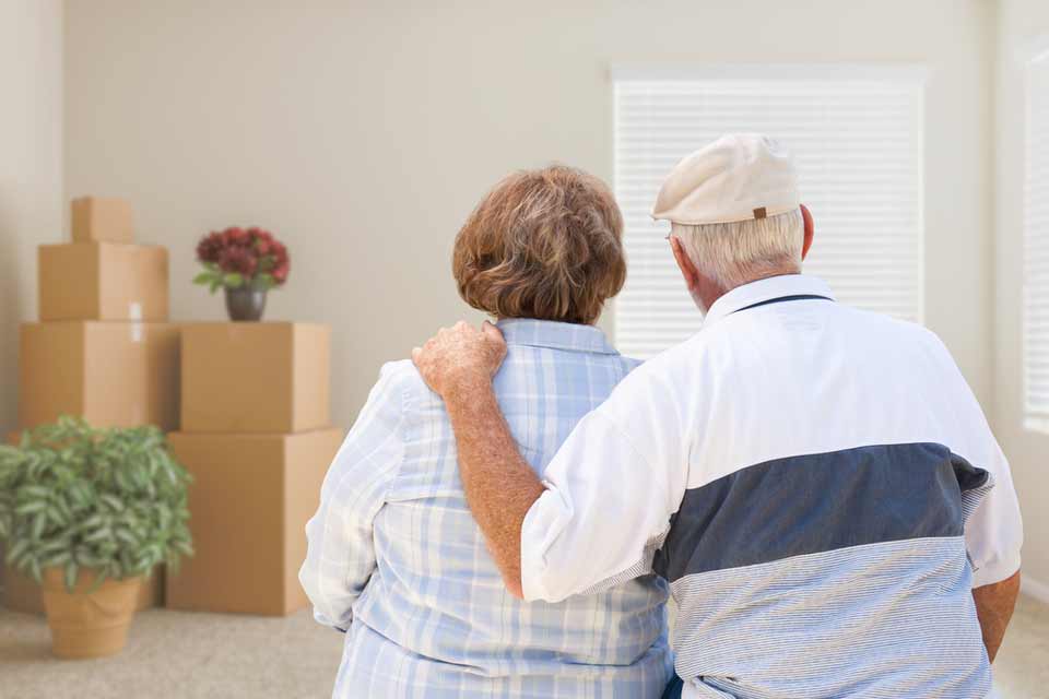 Elderly couple looking at their empty house and a few remaining boxes before they move out.